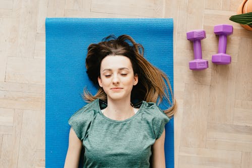 Free Smiling young woman meditating on yoga mat with closed eyes Stock Photo