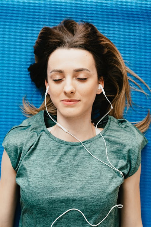 Free Young woman listening to music in earphones in apartment Stock Photo
