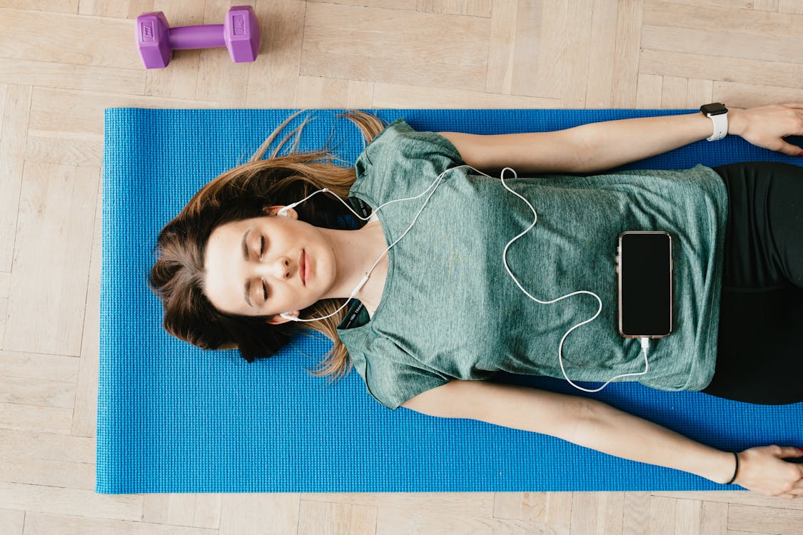 Free Peaceful woman in earphones resting in Shavasana pose at home Stock Photo