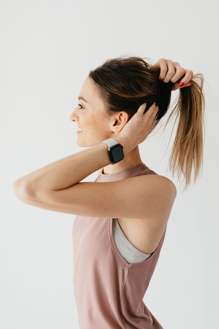 Positive Young Woman Collecting Hair In Tail