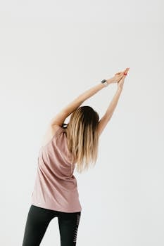 Young woman in yoga pose stretching muscles on a clean white background, promoting wellness and mindfulness.