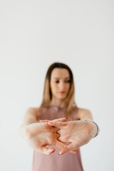 A young woman stretching her hands forward with focus and calmness in an indoor setting.