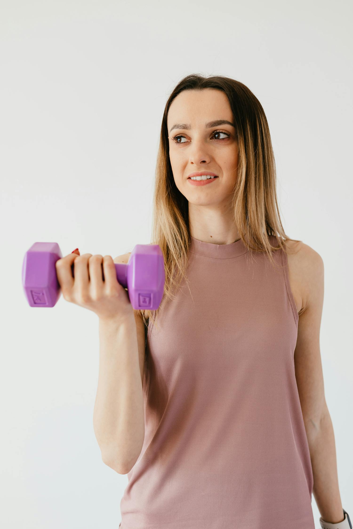Happy young sportswoman doing exercise with dumbbell