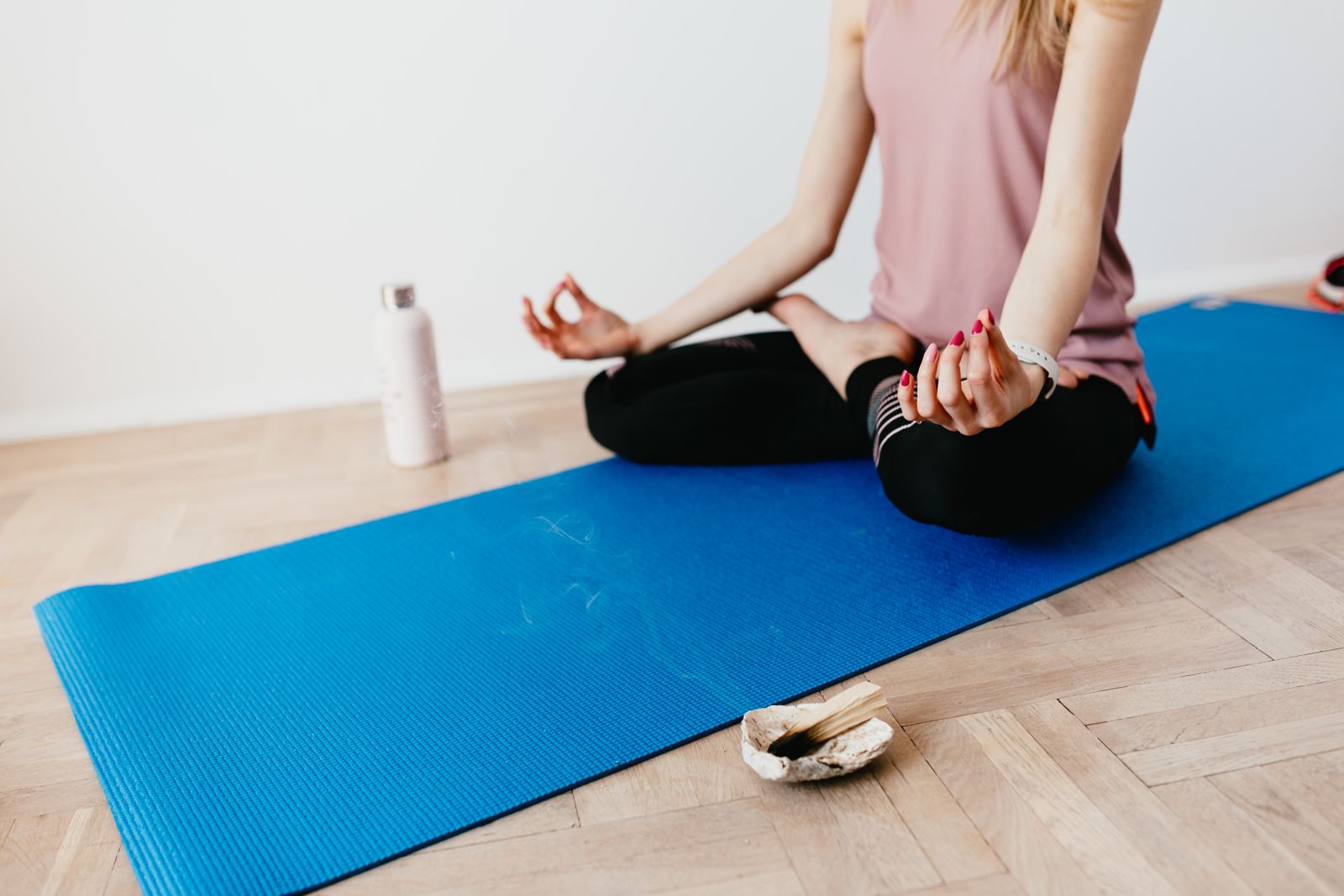 Person practicing hatha yoga in lotus pose on a blue yoga mat