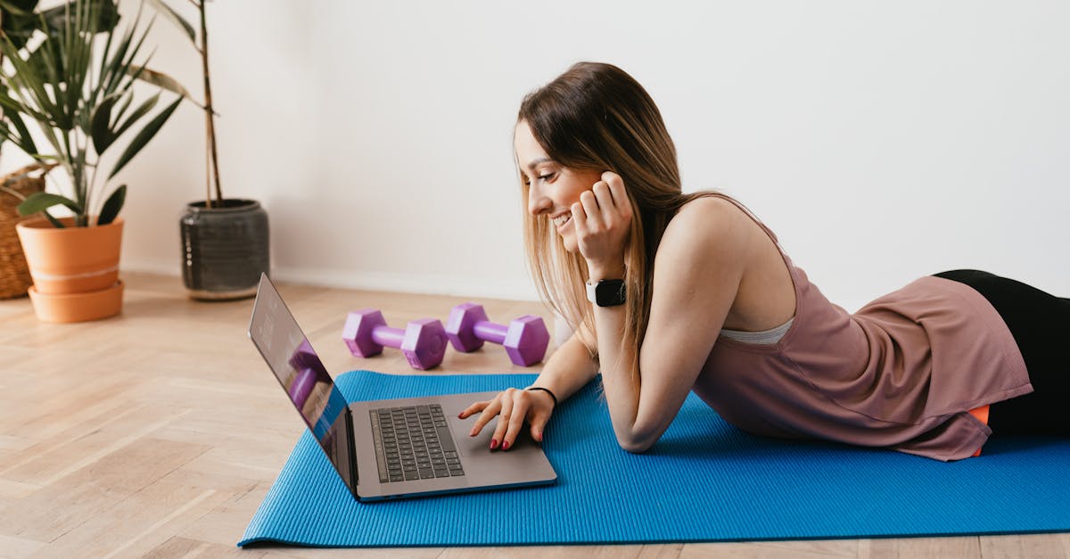 Slim woman browsing laptop on yoga mat · Free Stock Photo