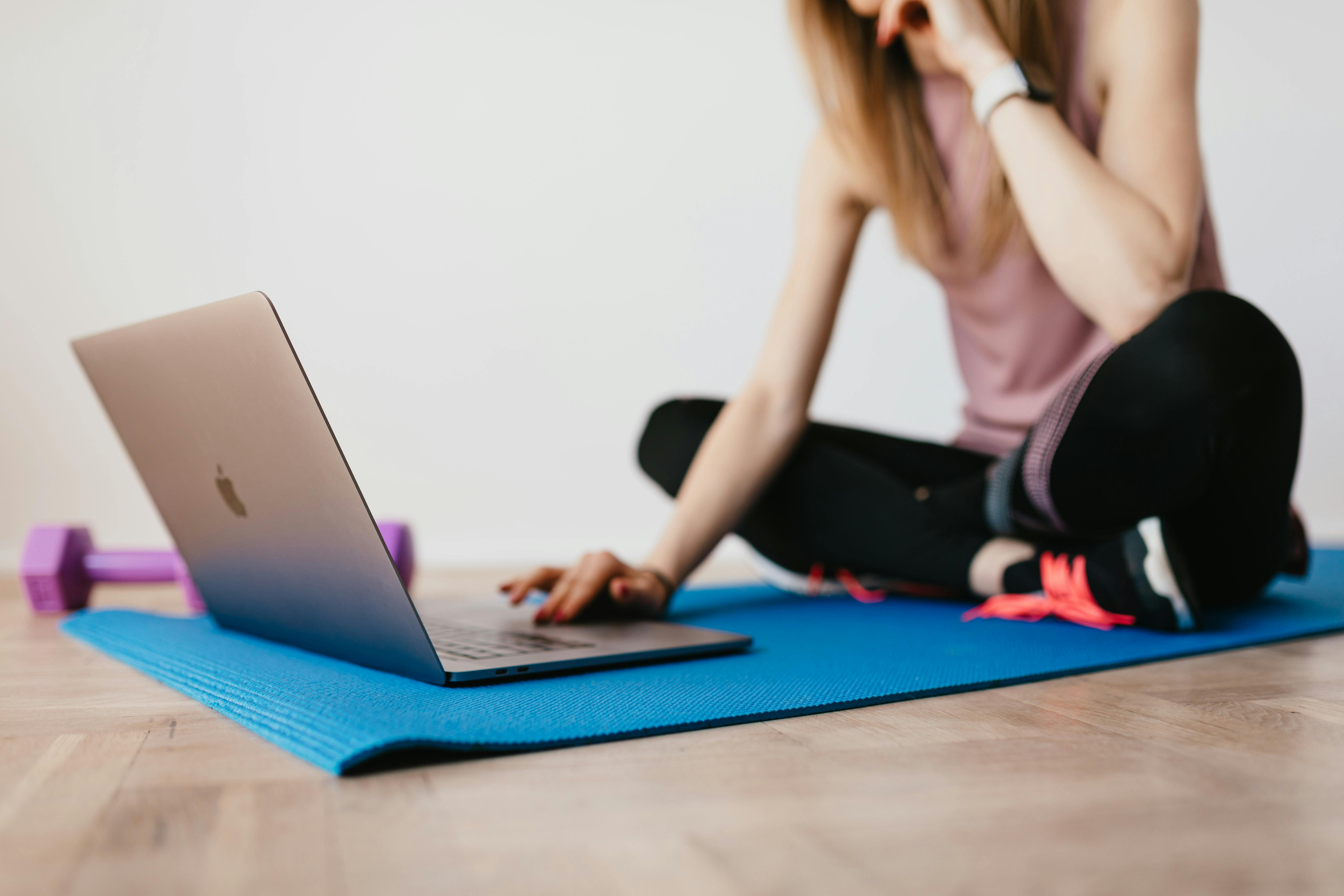 anonymous woman browsing laptop while sitting on mat