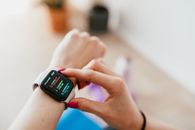 Faceless woman checking smartwatch and sitting on mat