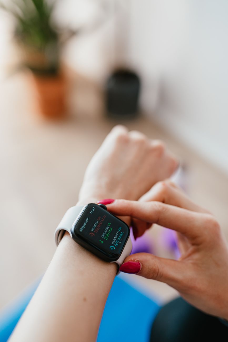 Anonymous female checking smartwatch while sitting on yoga mat