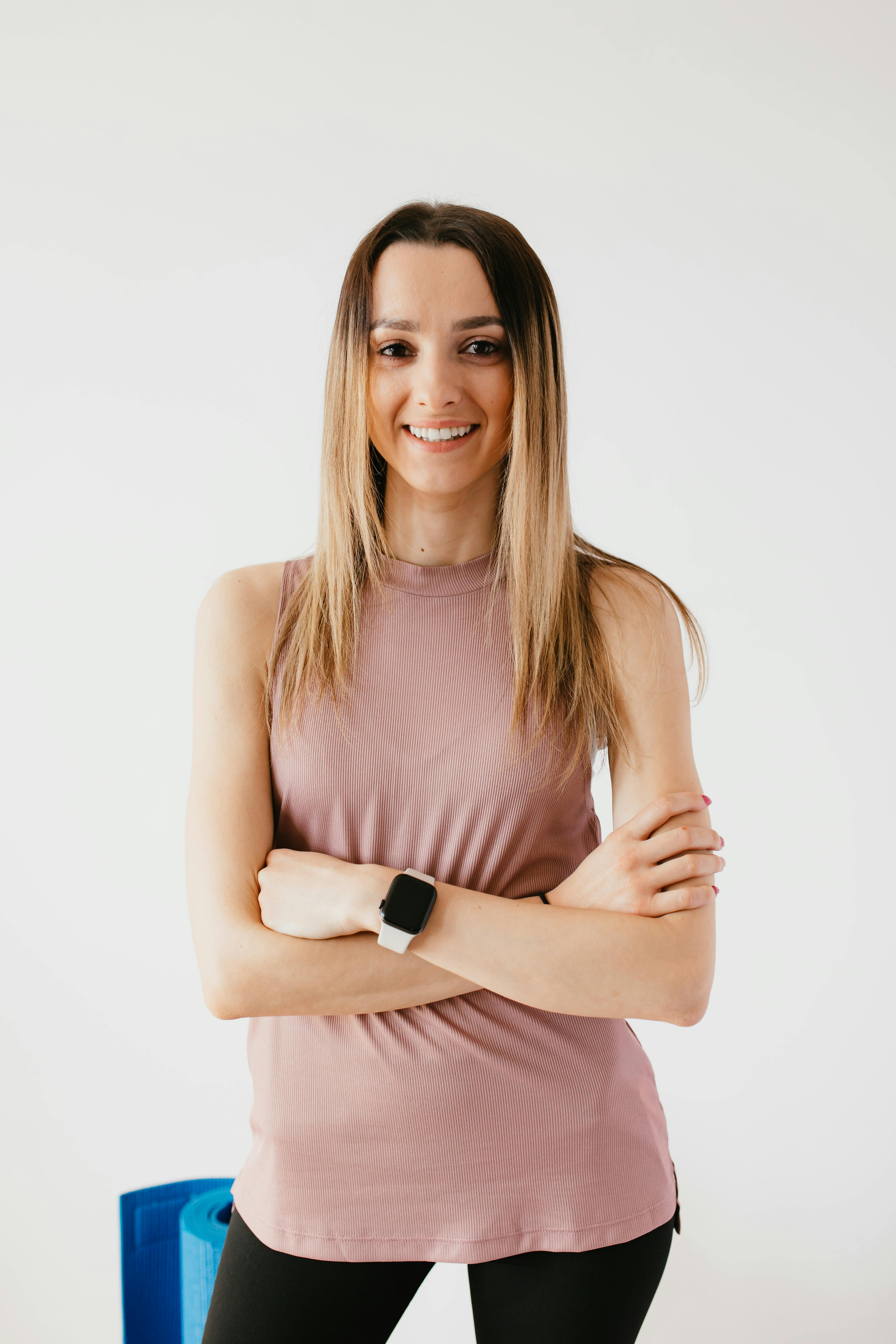 smiling sportswoman standing near wall and mat