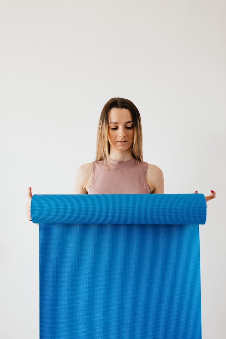 Focused Young Woman With Sport Mat Isolated On White Background