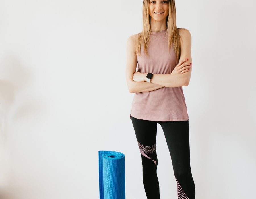 Yoga instructor standing calmly beside a mat
