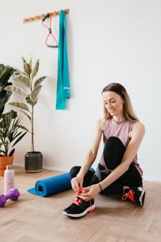 Young woman tying shoelaces in a home gym setting with fitness equipment.