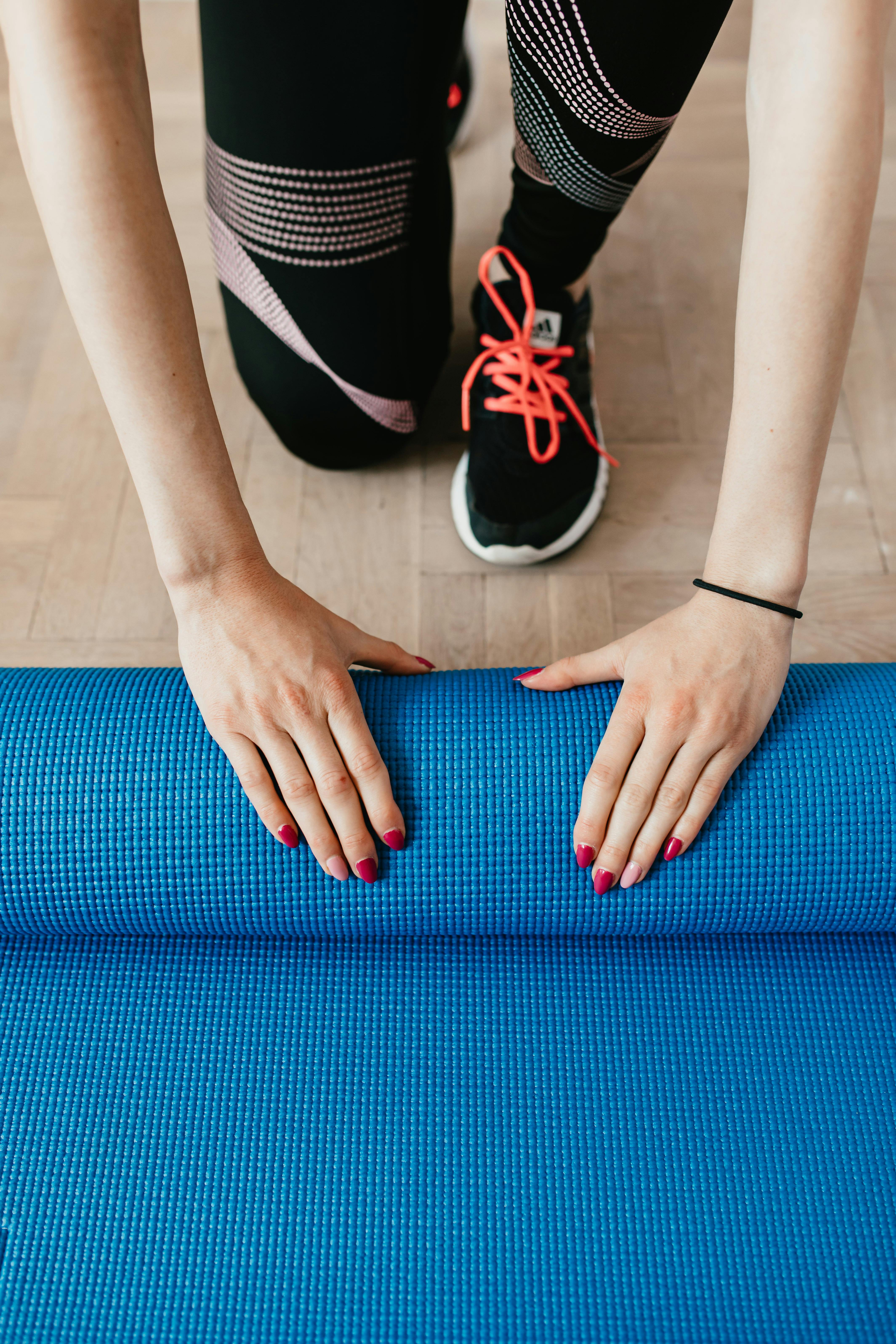 crop young sportswoman unfolding sport mat