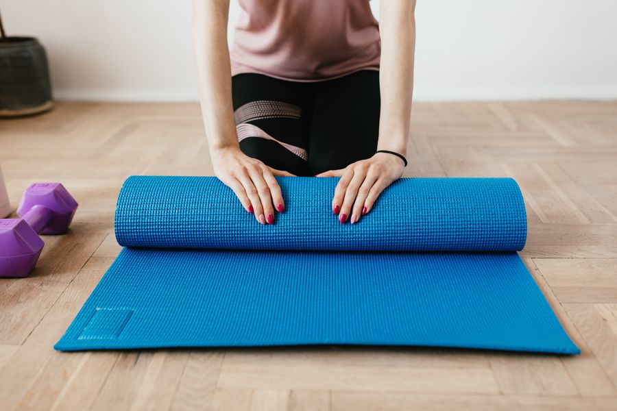 Woman unrolling a blue premium yoga exercise mat