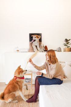 一名妇女在明亮的房间里，舒适地躺在床上和她的柴犬玩耍