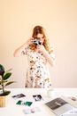 Woman in White and Red Floral Dress Holding Black Camera