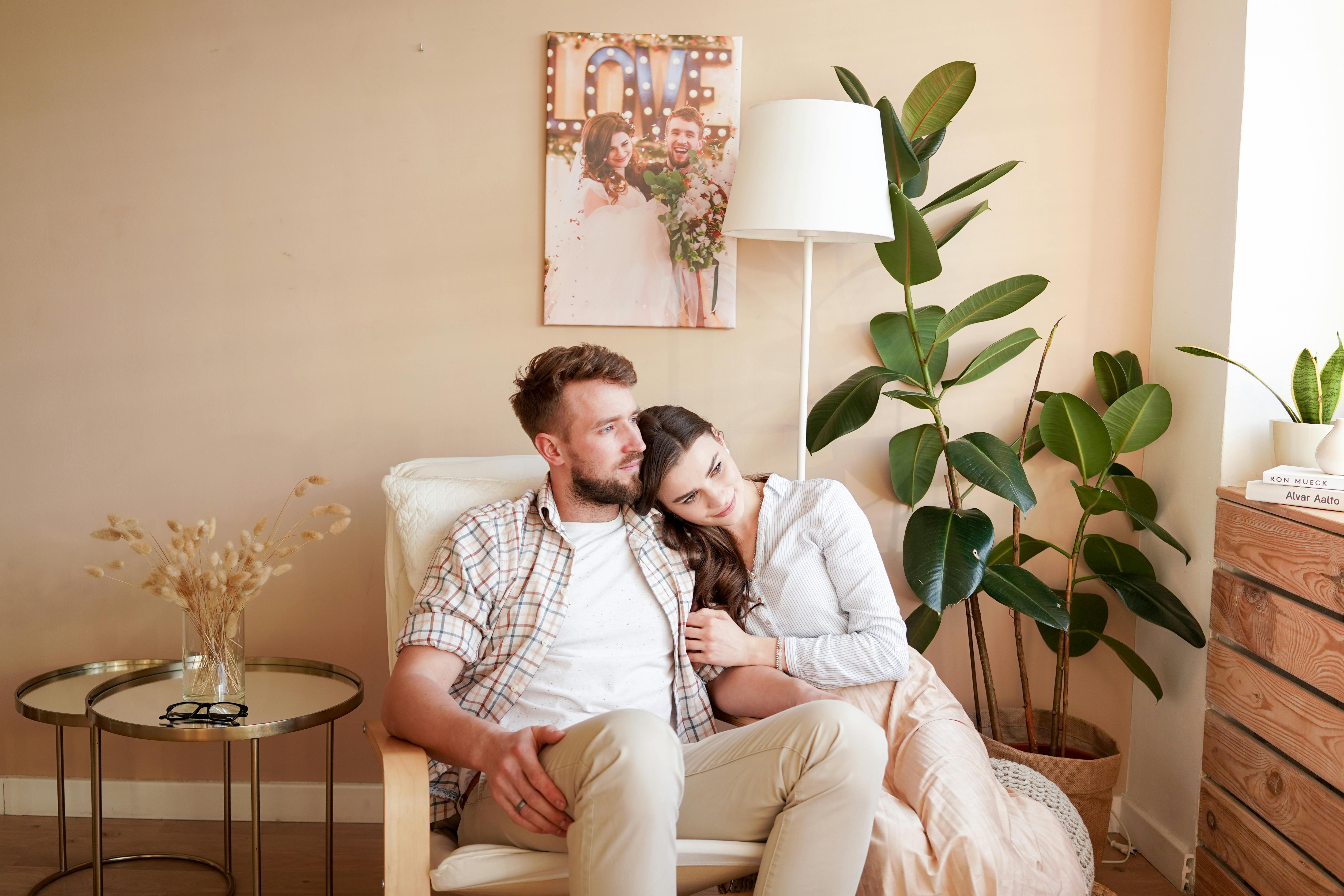 dreamy couple embracing in cozy armchair in flat in daylight