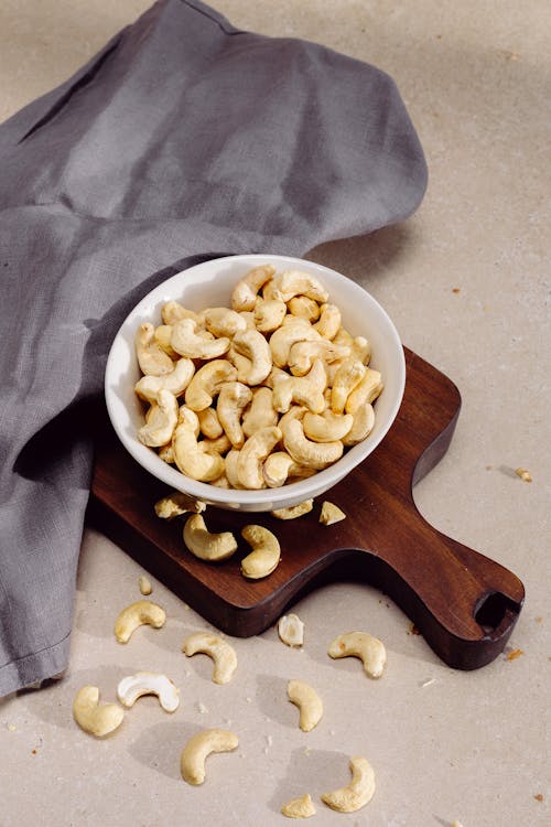 A Bowl with Cashews Standing on a Wooden Cutting Board