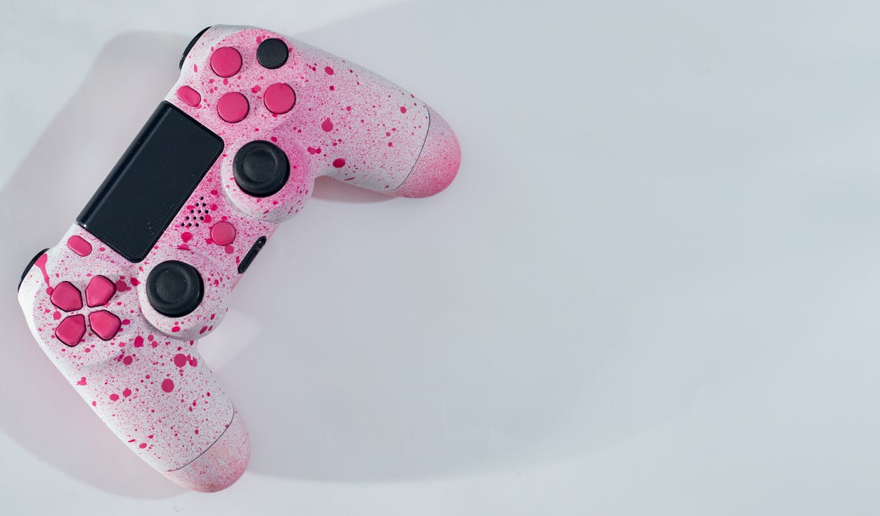 Free From above of bright controller with pink drops and knobs with buttons placed on white table while casting shadow in sunny day Stock Photo