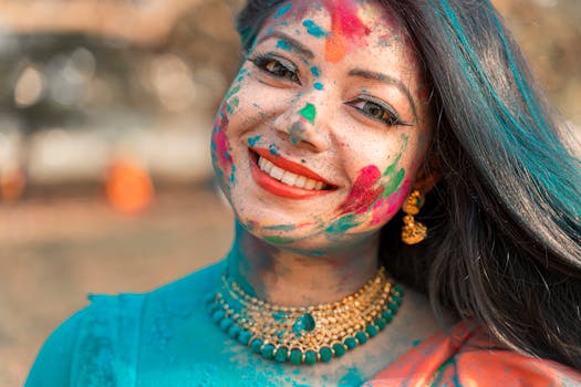 Smiling woman with colorful face during Holi festival in Kolkata, India.