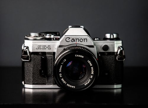 Free Closeup of vintage photo camera with black lens placed on dark table against gray wall in studio in spacious room Stock Photo