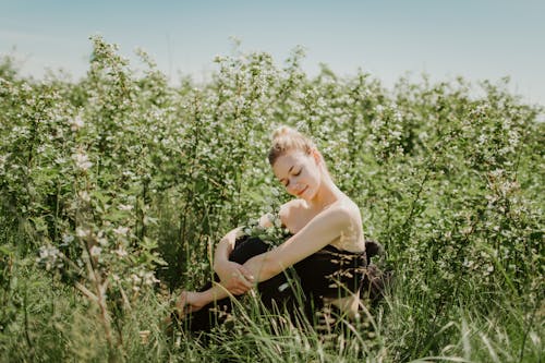 Woman in Black Tube Top Sitting on Green Grass Field