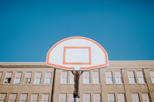 A basketball hoop with a backboard shot from a low angle against a clear blue sky.