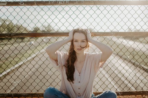 Wanita Dengan Sweater Rajut Coklat Dan Jeans Denim Biru Duduk Di Pagar Kayu Coklat