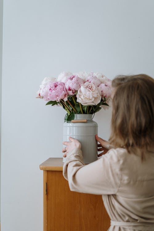 Girl in Pink Long Sleeve Shirt Holding Stainless Steel Jar With Pink Flowers