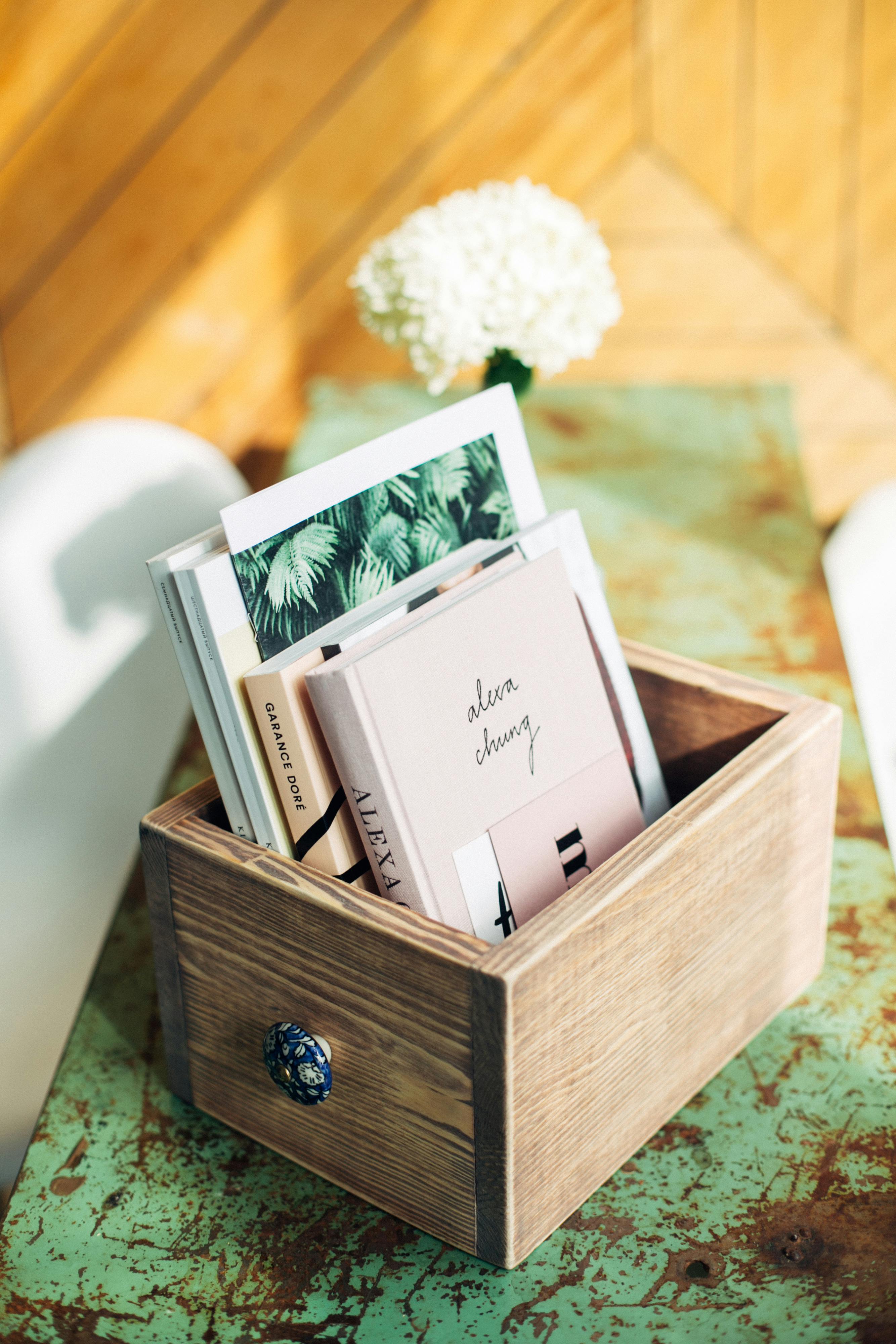 Free A wooden box filled with trendy books on a vintage green table, creating a cozy reading ambience. Stock Photo