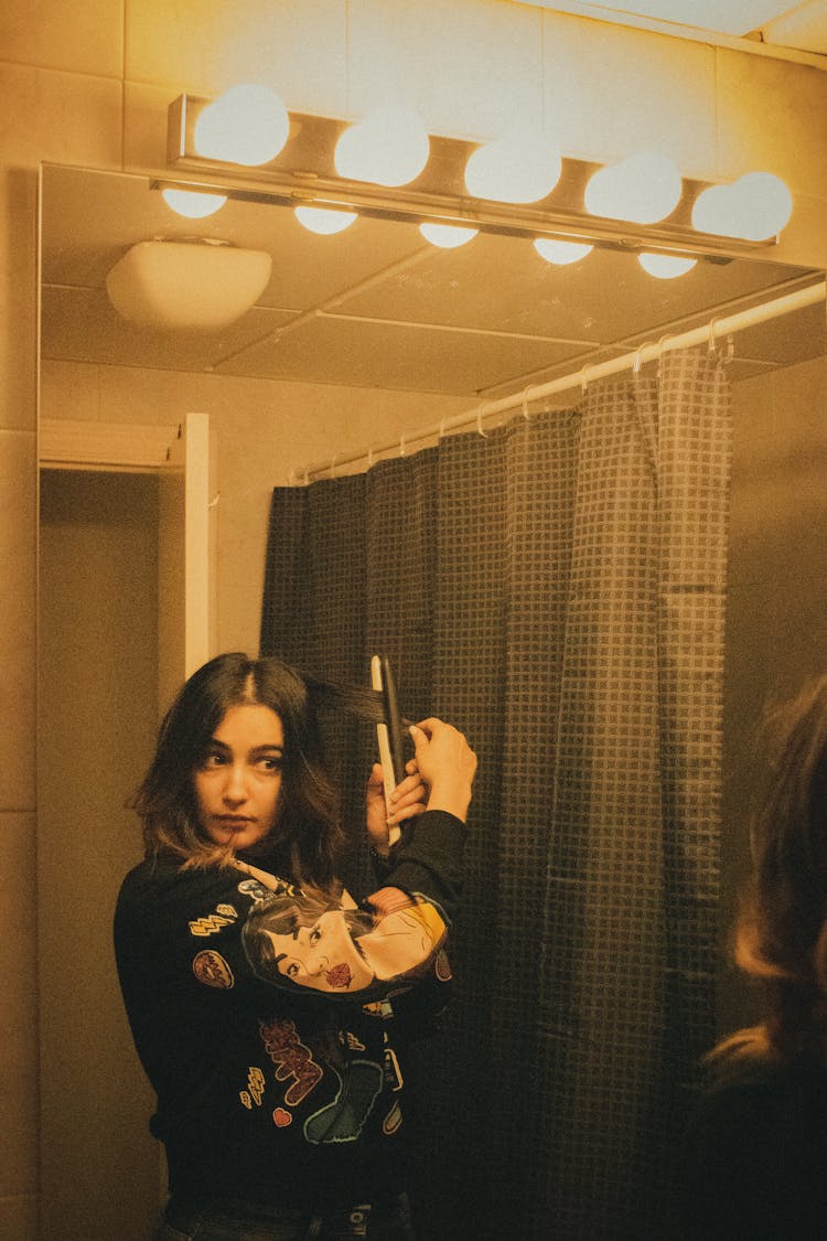 Young Woman Using Curling Hair In Bathroom