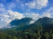 山脉的壮丽景色中，郁郁葱葱的绿色植物和戏剧性的云彩映衬着充满活力的蓝天