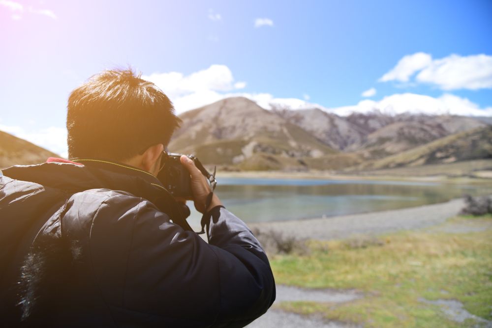 Photographer shooting a still lake beneath mountains