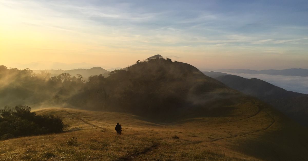 Hiker starting Mount Adaklu trail early morning with misty hills in background