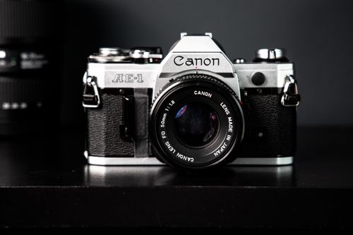 Free Close-up of a vintage Canon AE-1 SLR camera on a dark surface, showcasing classic photography nostalgia. Stock Photo