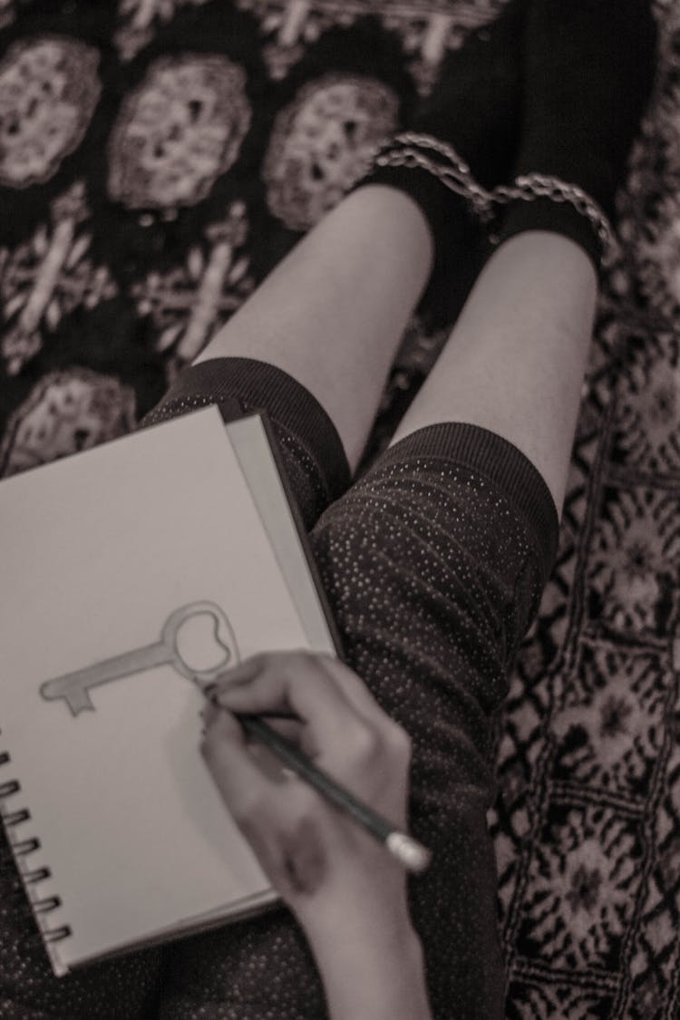 Person Holding A Pencil Drawing On A Spiral Notebook