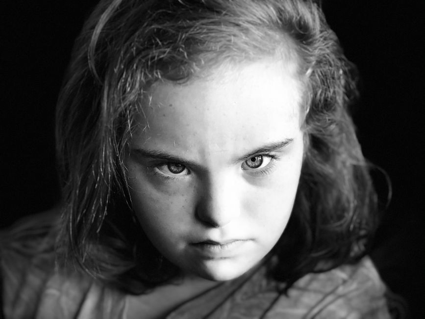 Captivating close-up black and white portrait of a young girl with intense gaze.
