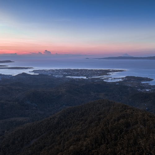 Ocean near mountains under bright sky at sunset