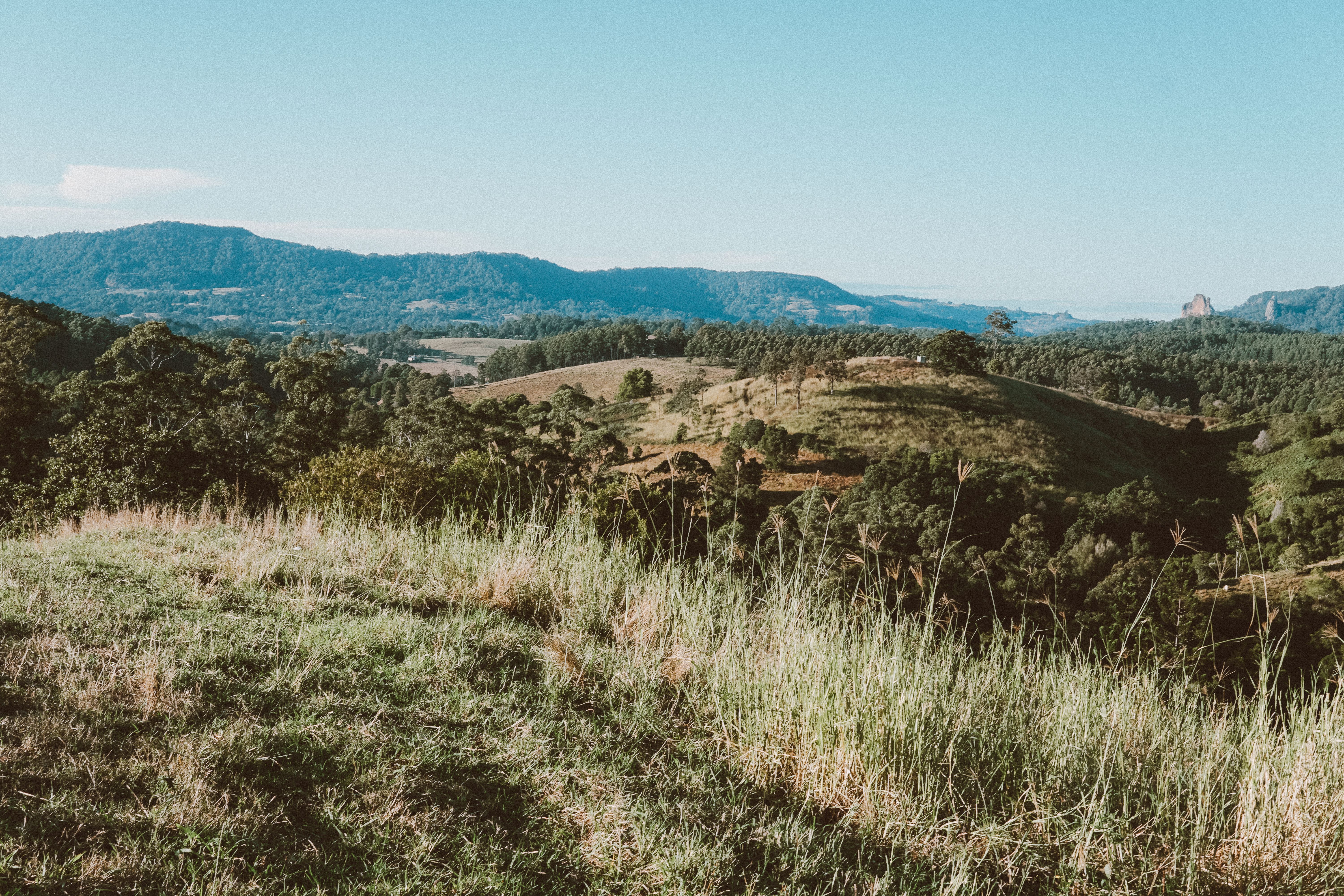 Green Grass Field Near Brown Mountain Under Blue Sky · Free Stock Photo