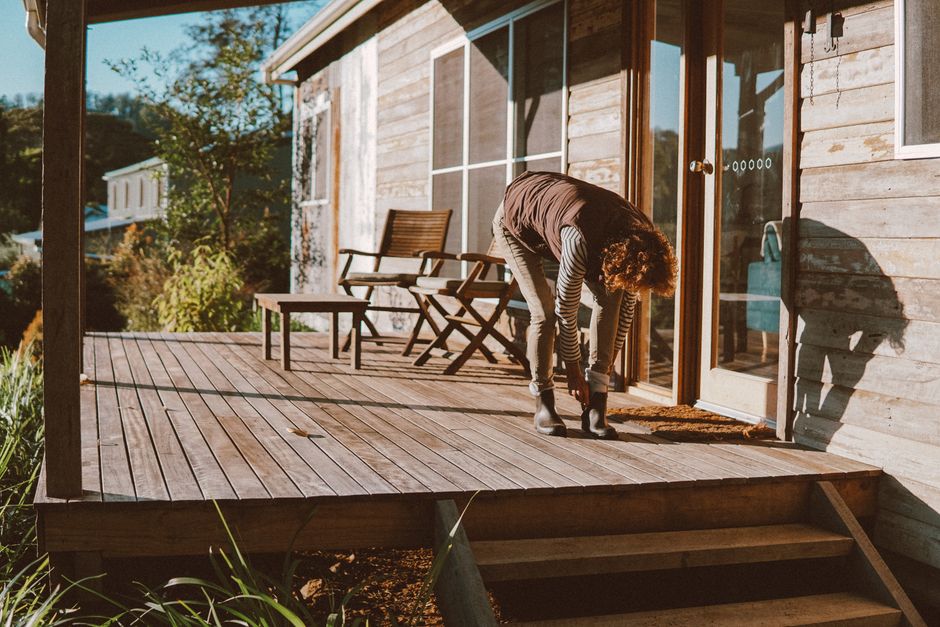 Photo by Elle Hughes on Pexels A woman putting on shoes on a wooden patio, capturing sunlight and rustic charm in Blue Knob, NSW.