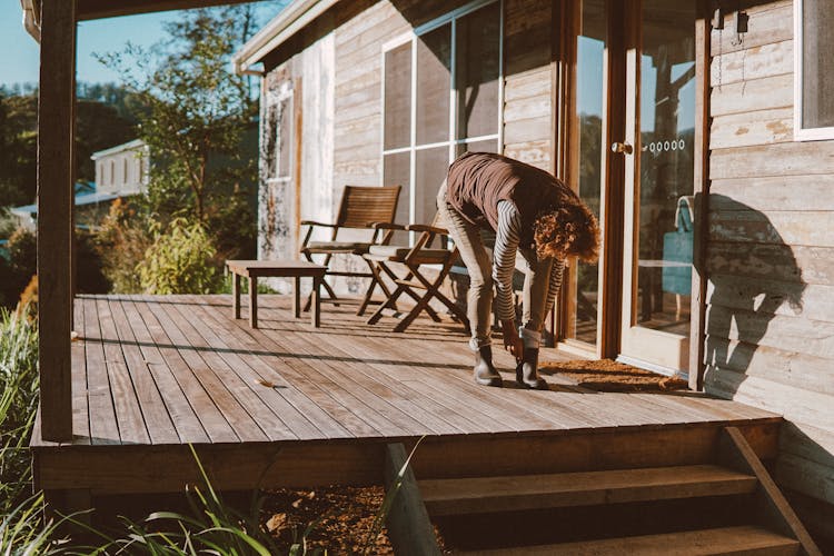 Woman Putting On Boots On The Patio