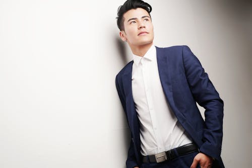 무료 파란색 재킷과 흰 벽에 기대어 흰색 드레스 셔츠를 입고 남자 스톡 사진