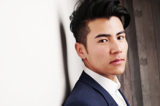 Close-up portrait of a serious Asian man in a formal suit indoors. Modern and professional look.