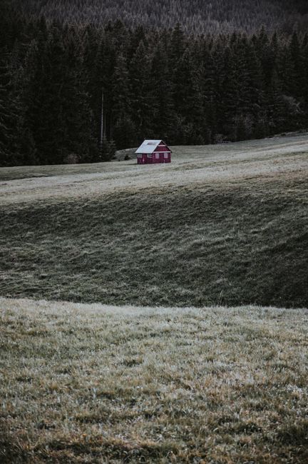 A serene red cabin nestled in the green rolling hills of Malá Úpa, Czech Republic.