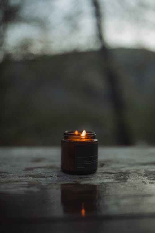 Free A Burning Candle in a Brown Glass Container Stock Photo