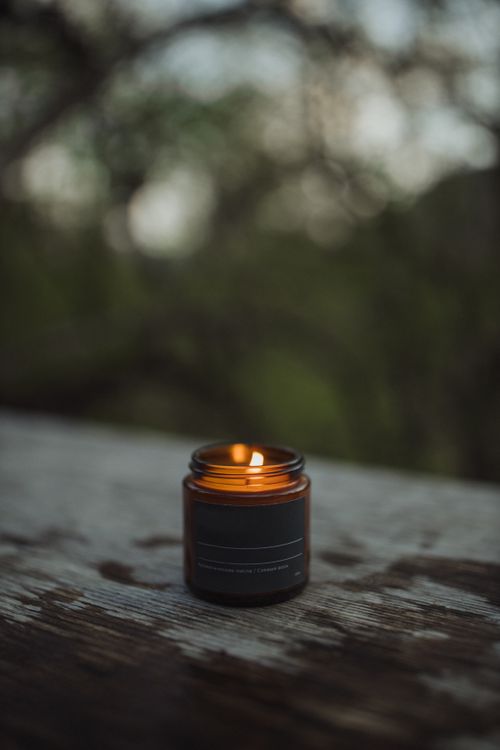Free A lit candle in a glass jar sits on a wooden surface, creating a warm ambiance. Stock Photo