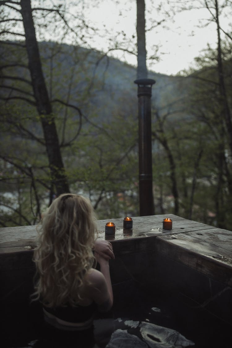 Woman With Blond Hair Near Lighted Candles In A Jar