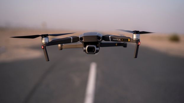 A high-tech drone hovers smoothly above a quiet Dubai road. Capturing the essence of modern technology.