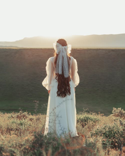 Femme En Robe Blanche Debout Sur Le Champ D'herbe Verte