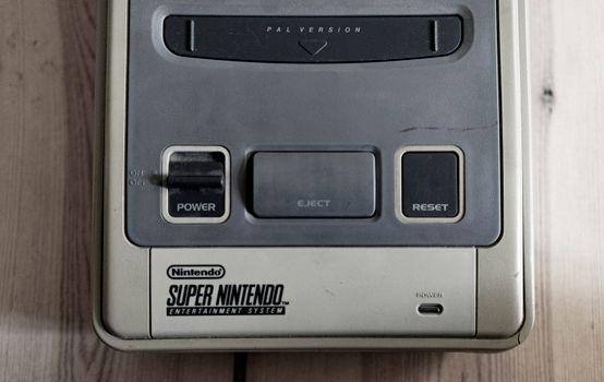 Old fashioned game console with buttons and words on plastic surface on wooden desk in flat